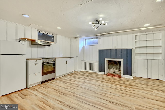 kitchen featuring wall oven, light hardwood / wood-style floors, white cabinets, and white fridge