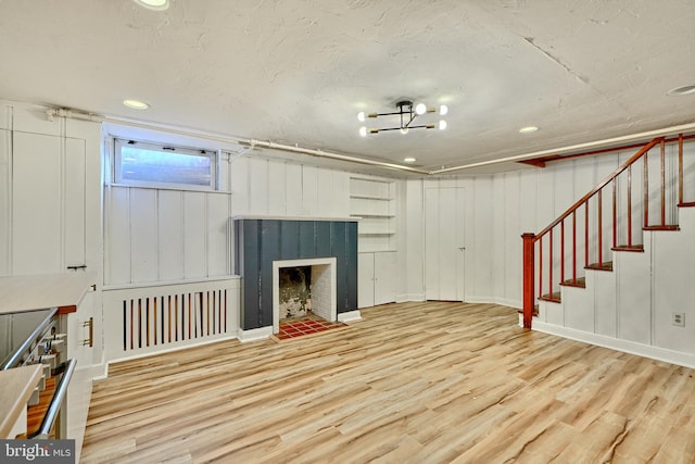 unfurnished living room featuring a fireplace, a textured ceiling, and light wood-type flooring