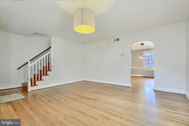 unfurnished living room with radiator heating unit and light hardwood / wood-style flooring