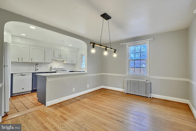 kitchen featuring radiator, kitchen peninsula, pendant lighting, white appliances, and white cabinets