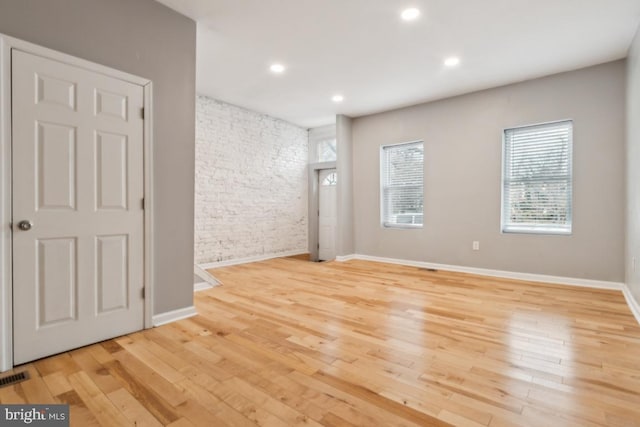 empty room with brick wall and light wood-type flooring