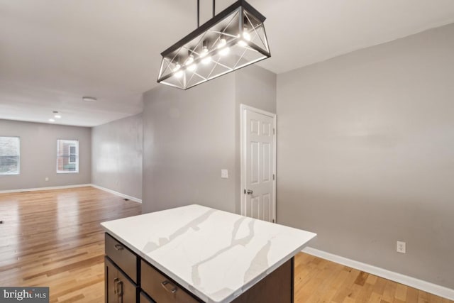 kitchen featuring light stone counters, decorative light fixtures, light hardwood / wood-style flooring, and a kitchen island