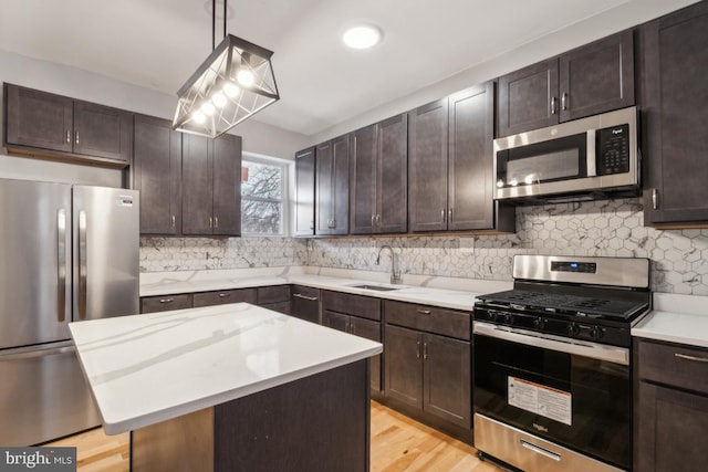 kitchen with a kitchen island, pendant lighting, tasteful backsplash, sink, and stainless steel appliances