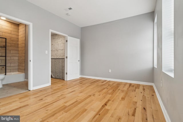 unfurnished bedroom featuring ensuite bathroom and light hardwood / wood-style floors