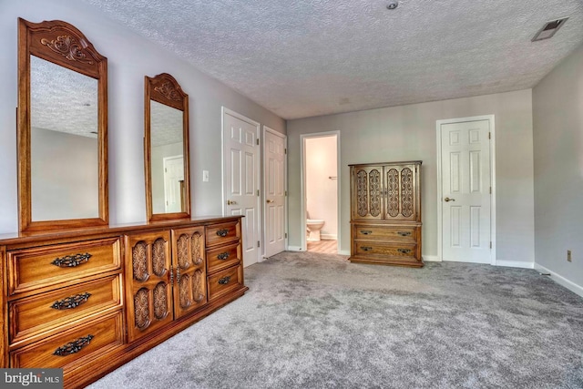 carpeted bedroom with connected bathroom and a textured ceiling