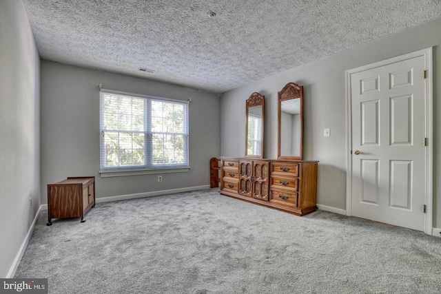 unfurnished bedroom with light colored carpet and a textured ceiling