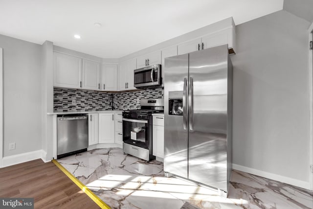 kitchen with stainless steel appliances, tasteful backsplash, and white cabinets