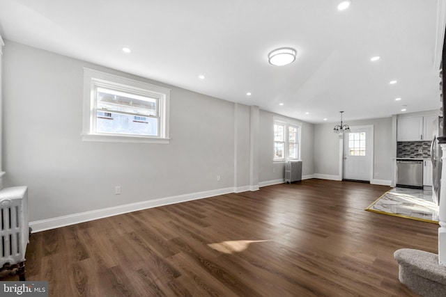 unfurnished living room featuring dark wood-type flooring and radiator heating unit