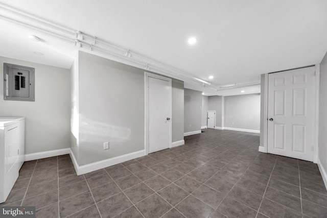 basement with dark tile patterned floors, washing machine and clothes dryer, and electric panel