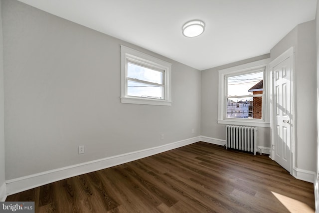 empty room with dark hardwood / wood-style flooring and radiator