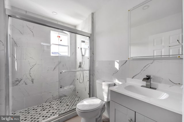 bathroom with vanity, tile walls, toilet, and walk in shower