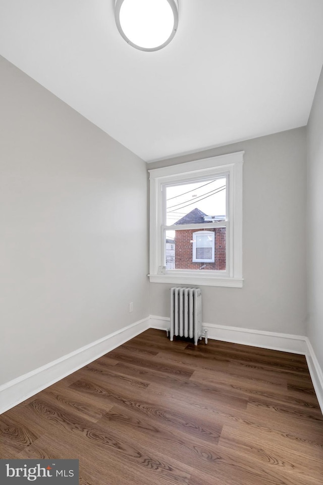 spare room featuring radiator and dark wood-type flooring