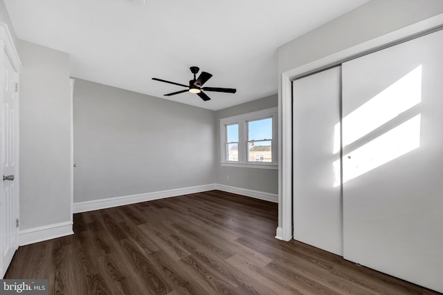 unfurnished bedroom with dark wood-type flooring, ceiling fan, and a closet