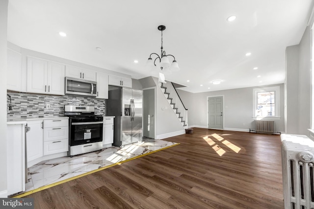 kitchen with white cabinetry, appliances with stainless steel finishes, dark hardwood / wood-style flooring, and radiator