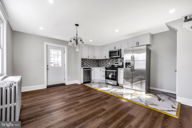 kitchen with radiator, decorative light fixtures, tasteful backsplash, white cabinets, and stainless steel appliances