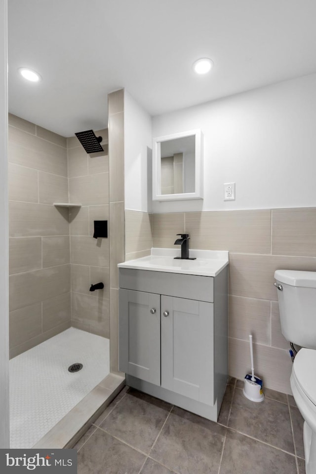 bathroom featuring tile patterned flooring, a tile shower, and toilet