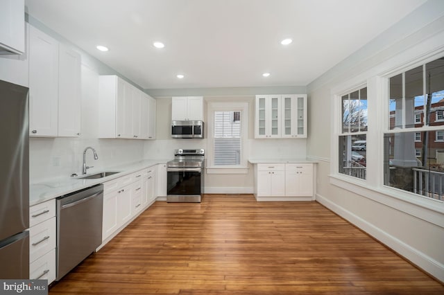 kitchen with sink, appliances with stainless steel finishes, white cabinetry, tasteful backsplash, and light wood-type flooring