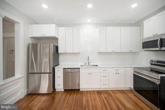 kitchen with white cabinetry, appliances with stainless steel finishes, sink, and wood-type flooring