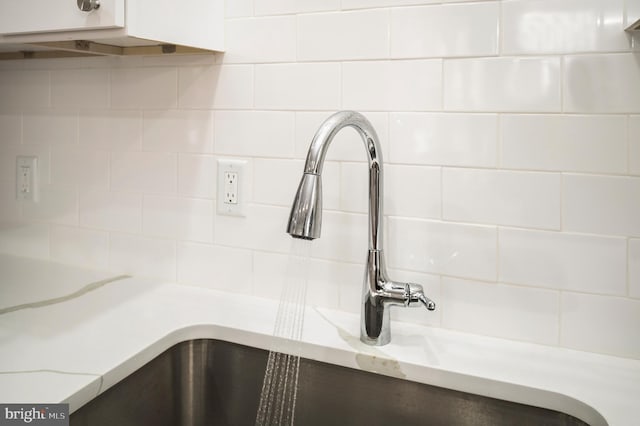 room details with light stone counters, sink, and white cabinets