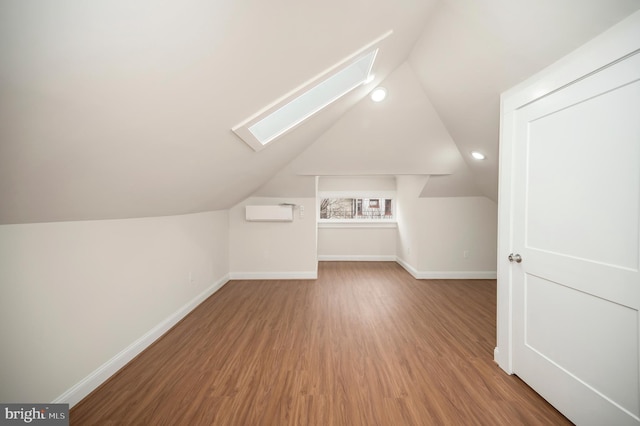 additional living space with hardwood / wood-style flooring and lofted ceiling with skylight