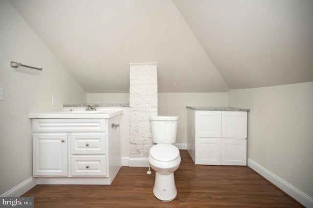 bathroom featuring vanity, lofted ceiling, hardwood / wood-style floors, and toilet