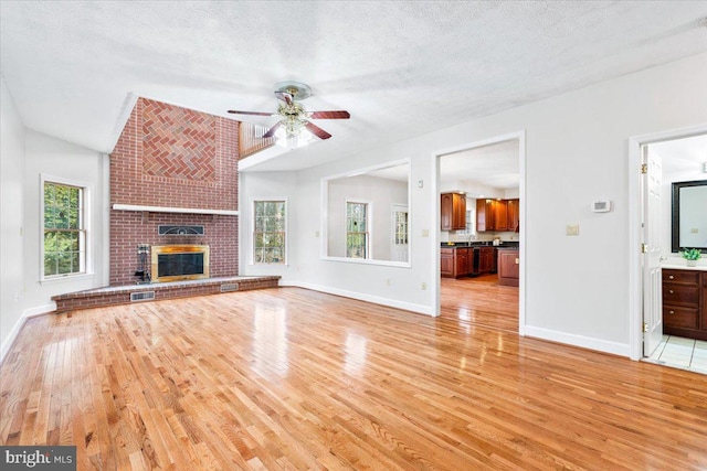 unfurnished living room with a fireplace, a wealth of natural light, and light wood-style floors