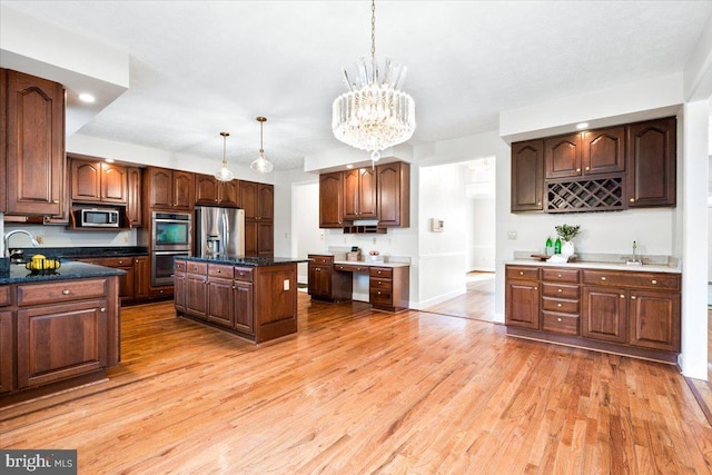 kitchen with dark brown cabinetry, a kitchen island, hanging light fixtures, stainless steel appliances, and light wood-style floors