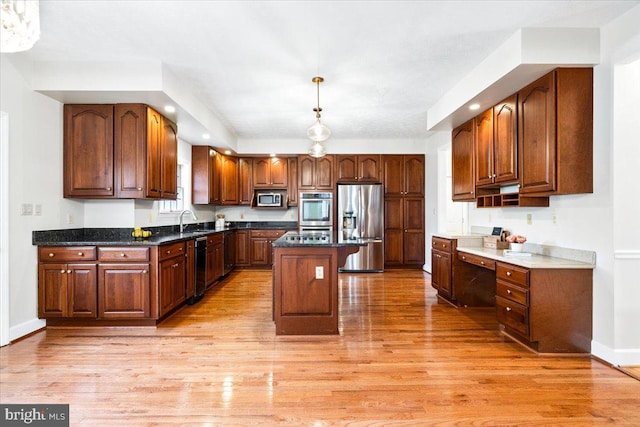 kitchen with a sink, stainless steel appliances, light wood finished floors, and a kitchen island