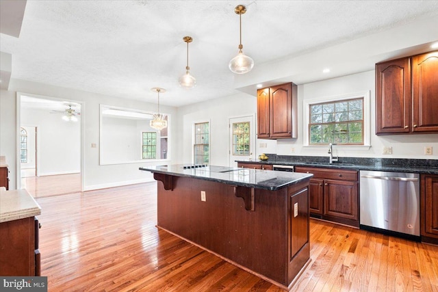 kitchen with a kitchen bar, a center island, hanging light fixtures, and stainless steel dishwasher