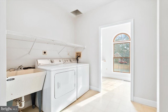 laundry area with laundry area, washer and clothes dryer, a sink, and baseboards