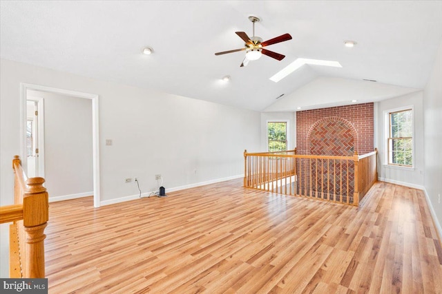 interior space with light wood-style floors, baseboards, lofted ceiling with skylight, and a wealth of natural light