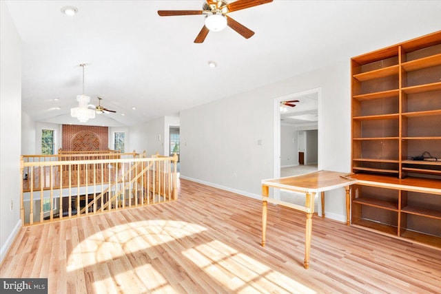 unfurnished room featuring vaulted ceiling, wood finished floors, an upstairs landing, and a wealth of natural light