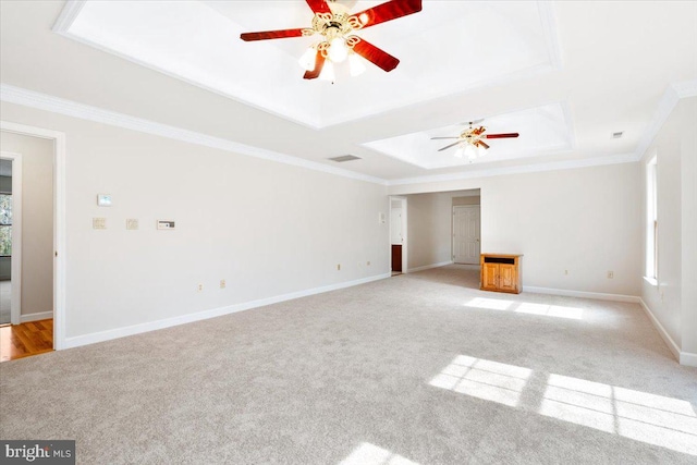 unfurnished living room featuring a tray ceiling, light colored carpet, crown molding, and baseboards