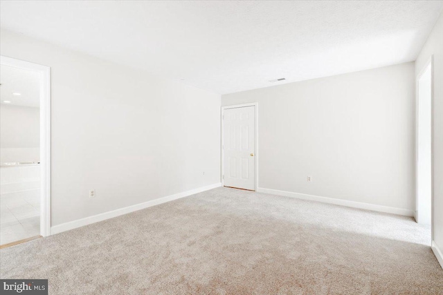 empty room featuring light carpet, visible vents, and baseboards