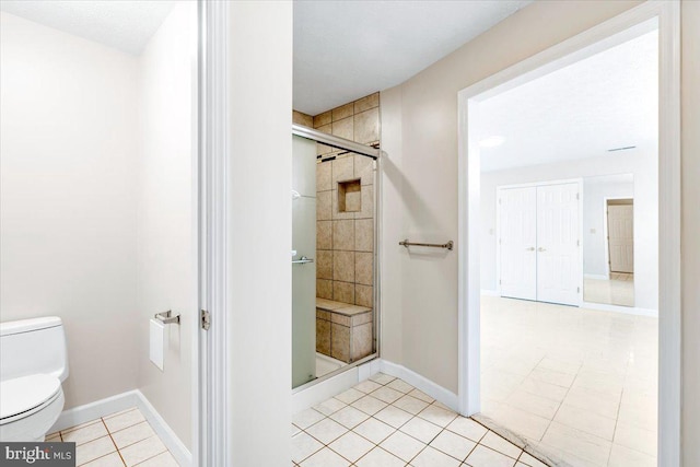 full bathroom featuring baseboards, a shower stall, toilet, and tile patterned floors