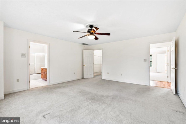 unfurnished bedroom featuring ensuite bath, visible vents, baseboards, and light colored carpet