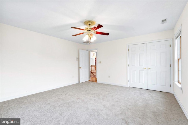 unfurnished bedroom featuring carpet flooring, visible vents, baseboards, a ceiling fan, and a closet