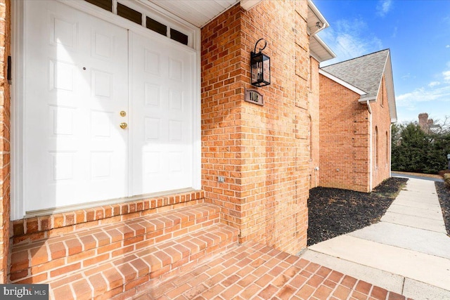 entrance to property with brick siding and roof with shingles