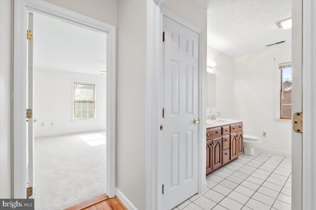 bathroom featuring baseboards, visible vents, toilet, a textured ceiling, and vanity