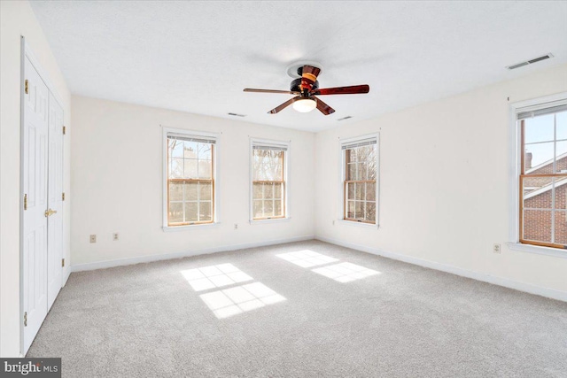 spare room featuring a healthy amount of sunlight, visible vents, and light colored carpet