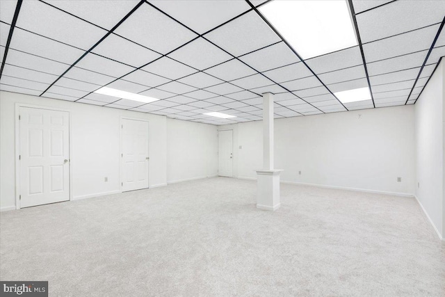 finished basement featuring baseboards, a drop ceiling, and light colored carpet