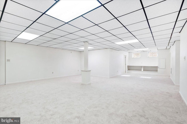 basement with carpet floors, a paneled ceiling, and baseboards