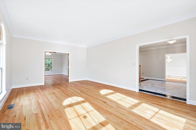 empty room with ornamental molding, wood finished floors, and baseboards