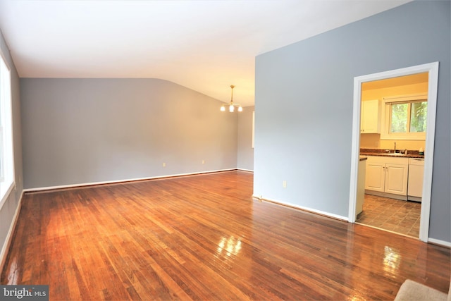 empty room with sink, a notable chandelier, vaulted ceiling, and light hardwood / wood-style floors