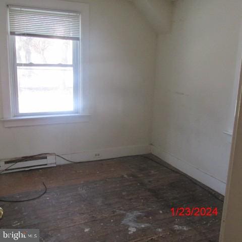 empty room with baseboard heating and wood-type flooring