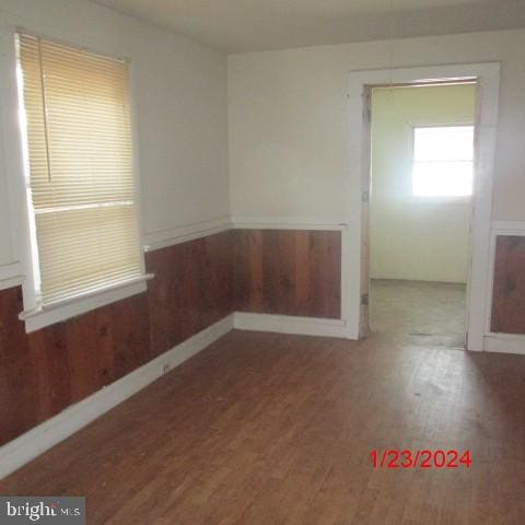 unfurnished room featuring hardwood / wood-style floors and wooden walls