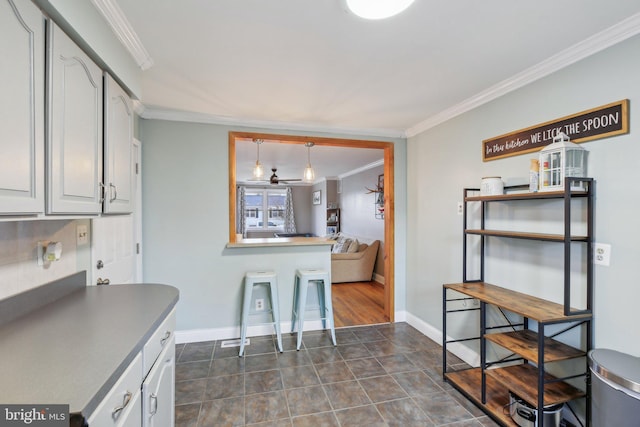 kitchen featuring pendant lighting, dark tile patterned floors, ornamental molding, and white cabinets