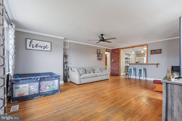 living room featuring hardwood / wood-style flooring, crown molding, and ceiling fan