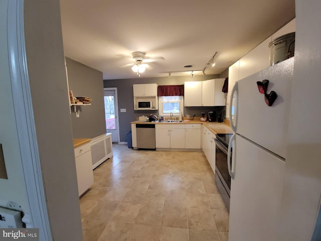 kitchen with radiator heating unit, white cabinetry, sink, ceiling fan, and stainless steel appliances