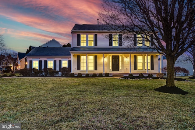 colonial home with a porch and a yard